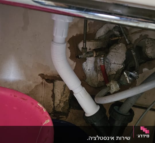 צינור ניקוז לבן מתחת לכיור עם דליים